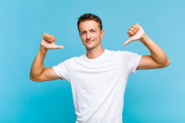 Genç yakışıklı adam üzgün, hayal kırıklığına uğramış ya da kızgın görünüyor, anlaşmazlık içinde baş parmağını gösteriyor, hayal kırıklığına uğramış hissediyor.