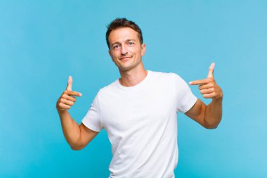 Genç yakışıklı adam gururlu, kibirli, mutlu, şaşırmış ve tatmin olmuş görünüyor, kendini gösteriyor, kazanan gibi hissediyor.