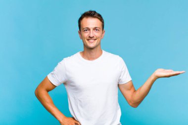 Genç yakışıklı adam gülümsüyor, kendinden emin, başarılı ve mutlu hissediyor, fotokopi alanında fikir veya konsept gösteriyor.