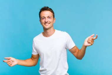 Genç yakışıklı adam gülümsüyor, kaygısız hissediyor, rahat ve mutlu, dans ediyor ve müzik dinliyor, bir partide eğleniyor.