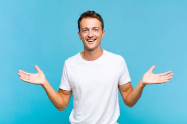 Genç yakışıklı adam mutlu, heyecanlı, şaşırmış ya da şok olmuş hissediyor, gülümsüyor ve hayrete düşüyor.