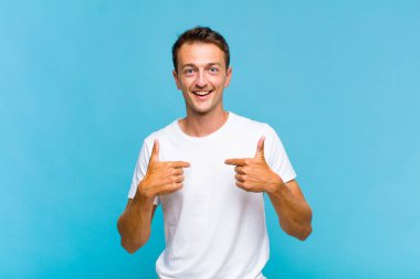 Genç yakışıklı adam mutlu, şaşkın ve gururlu, heyecanlı, şaşkın bakışlarıyla kendini işaret ediyor.