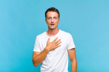 Genç yakışıklı adam şaşkın, şaşkın ve şaşırmış hissediyor, elleri göğsünde ve ağzı açık, kim diyor, ben mi??