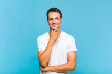 Genç yakışıklı adam gülümsüyor, hayattan zevk alıyor, mutlu, arkadaş canlısı, tatmin olmuş ve tasasız.