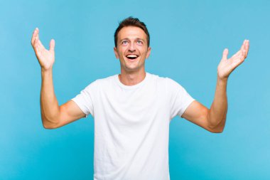 Genç yakışıklı adam kendini mutlu, şaşkın, şanslı ve şaşırmış hissediyor. Zaferi kutlarken iki elini de havaya kaldırıyor.