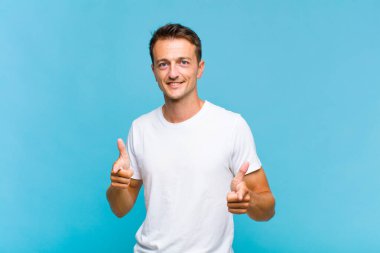 Genç yakışıklı adam kendini mutlu, havalı, tatmin olmuş, rahat ve başarılı hissediyor, kameraya bakıyor, seni seçiyor.