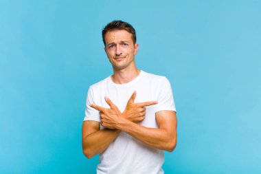 Şaşkın, kafası karışmış, güvensiz ve şüpheyle zıt yönlere bakan genç yakışıklı bir adam.