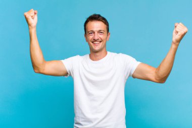 Genç yakışıklı adam zaferle bağırıyor. Heyecanlı, mutlu ve şaşırmış görünüyor. Kutlama yapıyor.