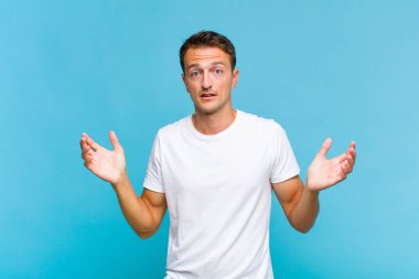 Genç yakışıklı adam şok olmuş ve şaşkın bakıyor, inanılmaz bir şey fark ettiğinde çenesi şaşkın şaşkın