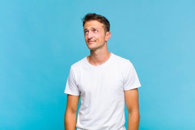 Genç ve yakışıklı adam kafası karışmış görünüyor, merak ediyor ya da bir sorunu çözmeye çalışıyor ya da düşünüyor.