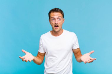 Genç, yakışıklı, ağzı açık ve şaşkın, şok olmuş ve şaşırmış bir adam.