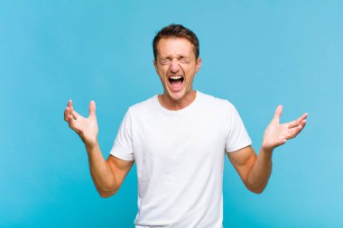 Genç yakışıklı adam öfkeyle bağırıyor, stresli hissediyor ve ellerini havaya kaldırıp neden ben diye bağırıyor.