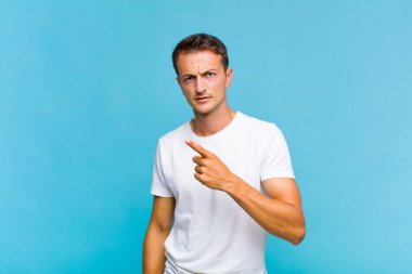 Genç yakışıklı bir adam kızgın agresif bir ifadeyle kameraya bakıyor. Öfkeli, çılgın bir patron gibi görünüyor.