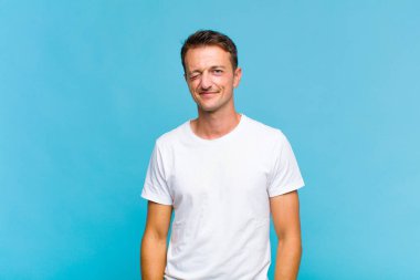 Genç yakışıklı adam mutlu ve arkadaş canlısı görünüyor, gülümsüyor ve sana olumlu bir tavırla göz kırpıyor.