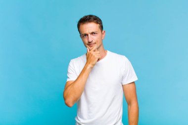 Genç yakışıklı adam ciddi görünüyor, kafası karışık, kararsız ve düşünceli, seçenekler ve seçimler arasında şüpheci.