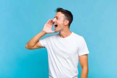 Genç yakışıklı adam öfkeyle bağırıyor kenardaki boşluğu kopyalasın diye, eli ağzının yanında.