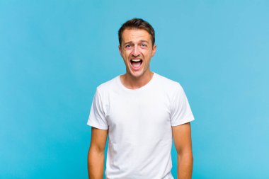 Genç yakışıklı adam korkmuş ve şok olmuş hissediyor, ağzı açık şaşkınlık içinde.