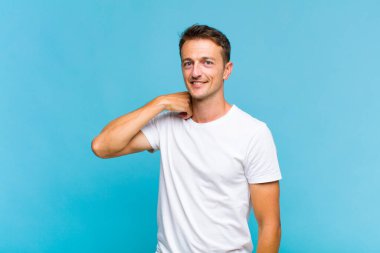 Genç ve yakışıklı bir adam neşeli ve kendinden emin bir şekilde gülüyor. Sıradan, mutlu, samimi bir gülümsemeyle.