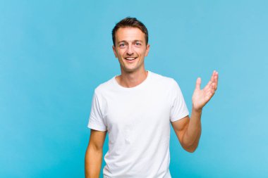 Genç yakışıklı adam kendini mutlu, şaşırmış ve neşeli hissediyor. Pozitif bir tavırla gülümsüyor. Bir çözüm ya da fikir buluyor.