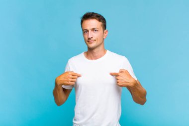 Genç yakışıklı adam gururlu, pozitif ve iki eliyle göğsünü gösteren