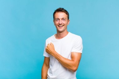 Genç yakışıklı adam mutlu, pozitif ve başarılı hissediyor, bir meydan okumayla karşılaştığında motive oluyor veya iyi sonuçları kutluyor.