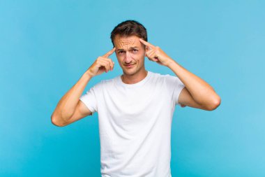 Ciddi ve konsantre görünümlü, beyin fırtınası yapan ve zorlu bir sorunu düşünen genç yakışıklı bir adam.