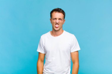 Genç yakışıklı adam tiksinmiş ve rahatsız olmuş hissediyor. Dilini dışarı çıkarıyor. İğrenç ve iğrenç bir şeyden hoşlanmıyor.