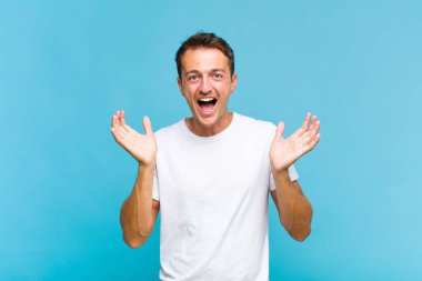 Genç ve yakışıklı bir adam beklenmedik bir sürpriz yüzünden şaşkın ve heyecanlı, güler yüzlü, şaşkın ve mutlu hissediyor.