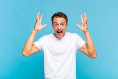 Genç yakışıklı adam elleri havada bağırıyor, öfkeli, sinirli, stresli ve üzgün hissediyor.