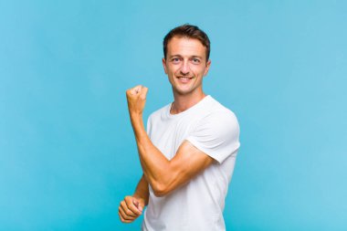 Genç yakışıklı adam kendini mutlu, tatmin olmuş ve güçlü hissediyor, kaslı ve formda, spor salonundan sonra güçlü görünüyor.