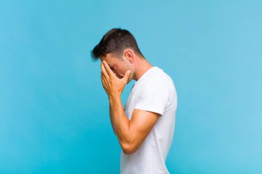 Genç yakışıklı adam üzgün, hayal kırıklığına uğramış bir bakışla gözlerini kapatıyor umutsuzluk, ağlama, yan bakış