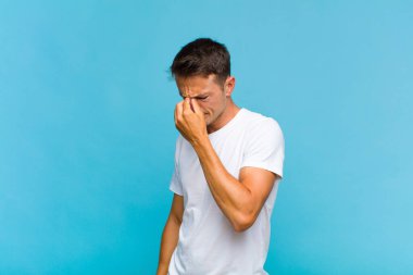 Genç yakışıklı, stresli, mutsuz ve hayal kırıklığına uğramış, alınlı ve şiddetli baş ağrısı çeken bir adam.