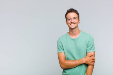 Genç yakışıklı adam utangaç ve neşeli bir şekilde gülüyor, arkadaş canlısı ve olumlu ama güvensiz bir tavırla.