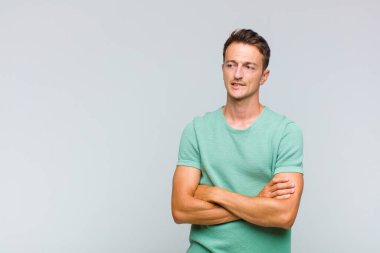 Genç yakışıklı adam şüphe ediyor ya da düşünüyor, dudağını ısırıyor ve kendini güvensiz ve gergin hissediyor, kenarda yer arıyor.