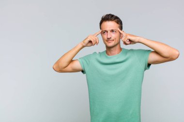 Genç ve yakışıklı bir adam kafası karışmış ya da şüphe içinde, bir fikre odaklanmış, çok düşünüyor, kenarda boşluğu kopyalamaya çalışıyor.