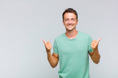 Genç ve yakışıklı adam neşeyle gülümsüyor ve mutlu görünüyor, kaygısız ve pozitif hissediyor.