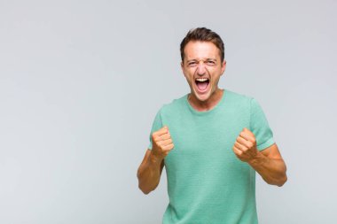 Genç yakışıklı adam sinirli, sinirli, sinirli bakışlar ve sıkı yumruklar ile agresif bir şekilde bağırıyor.