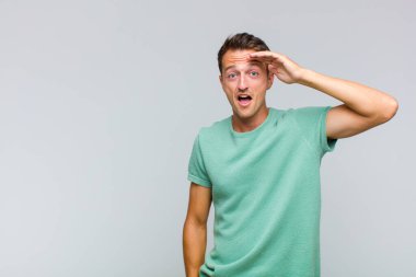 Genç yakışıklı adam mutlu, şaşkın ve şaşırmış görünüyor, gülümsüyor ve inanılmaz ve inanılmaz iyi haberleri fark ediyor.