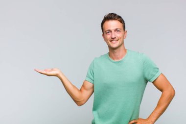 Genç yakışıklı adam gülümsüyor, kendinden emin, başarılı ve mutlu hissediyor, fotokopi alanında fikir veya konsept gösteriyor.