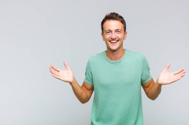 Genç yakışıklı adam mutlu, heyecanlı, şaşırmış ya da şok olmuş hissediyor, gülümsüyor ve hayrete düşüyor.