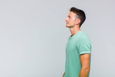 Profil görünümündeki genç yakışıklı adam ilerideki boşluğu kopyalamaya çalışıyor, düşünüyor, hayal ediyor ya da hayal kuruyor.