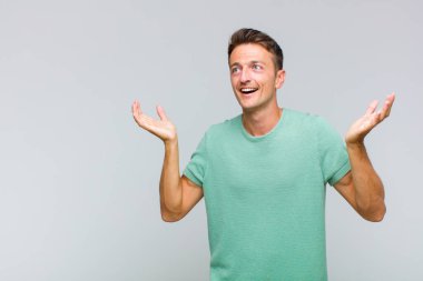 Genç yakışıklı adam kendini mutlu, şaşkın, şanslı ve şaşırmış hissediyor. Zaferi kutlarken iki elini de havaya kaldırıyor.