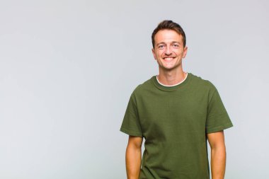 Genç yakışıklı adam mutlu ve şapşal görünüyor. Geniş, eğlenceli, kaçık bir gülüşü ve açık gözleri var.