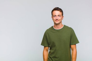 Genç yakışıklı adam pozitif ve kendinden emin gülümsüyor. Tatmin olmuş, arkadaş canlısı ve mutlu görünüyor.