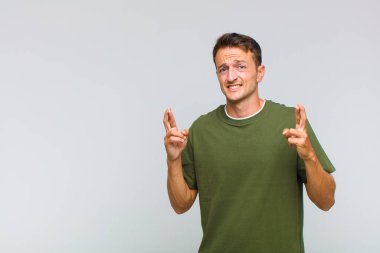 Genç yakışıklı adam endişeyle dua ediyor ve endişeli bir bakışla iyi şanslar diliyor.