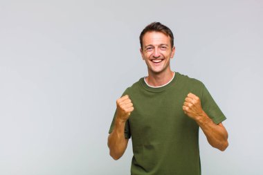 Genç yakışıklı adam zaferle bağırıyor, gülüyor, mutlu ve heyecanlı hissediyor başarıyı kutlarken.