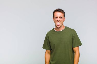 Genç yakışıklı adam tiksinmiş ve rahatsız olmuş hissediyor. Dilini dışarı çıkarıyor. İğrenç ve iğrenç bir şeyden hoşlanmıyor.