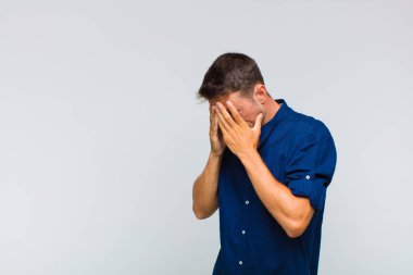 Genç yakışıklı adam üzgün, hayal kırıklığına uğramış bir bakışla gözlerini kapatıyor umutsuzluk, ağlama, yan bakış