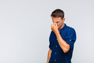 Genç yakışıklı, stresli, mutsuz ve hayal kırıklığına uğramış, alınlı ve şiddetli baş ağrısı çeken bir adam.