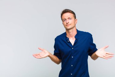 Genç yakışıklı adam şaşkın ve şaşkın hissediyor, doğru cevap veya karardan emin değil, bir seçim yapmaya çalışıyor.